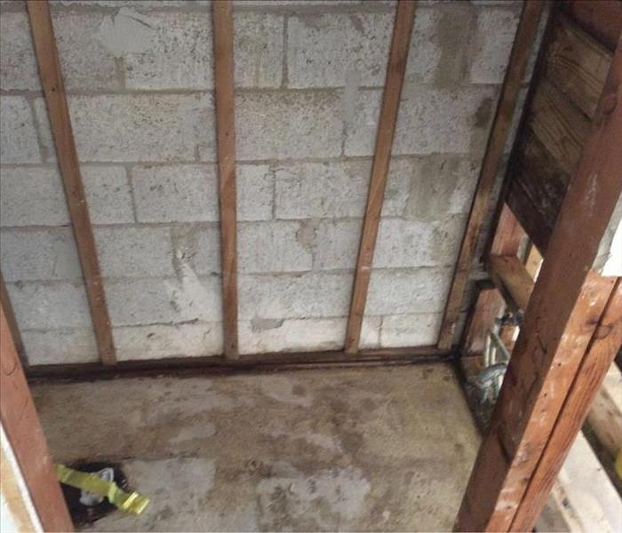 Drywall removed visible concrete walls with wooden studs
