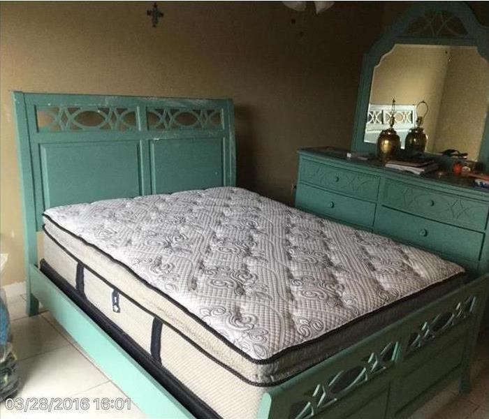 Clean mattress on teal bed with teal dresser