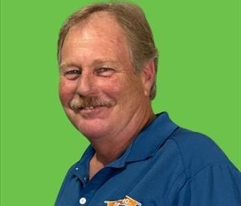 Man in dark blue shirt in front of green background.