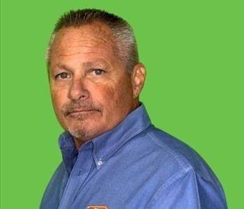 Man in button down light blue shirt in front of green background.